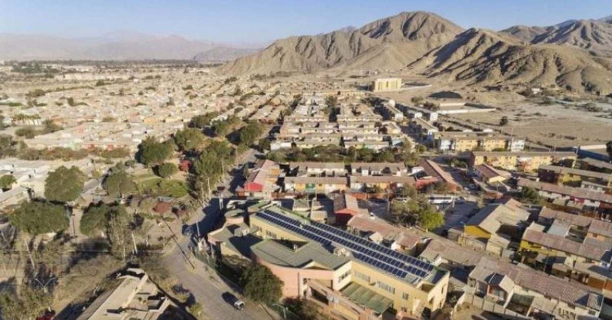 Vista aérea de una ciudad del valle de Copiapó rodeada de cerros áridos, con paneles solares sobre los techos.