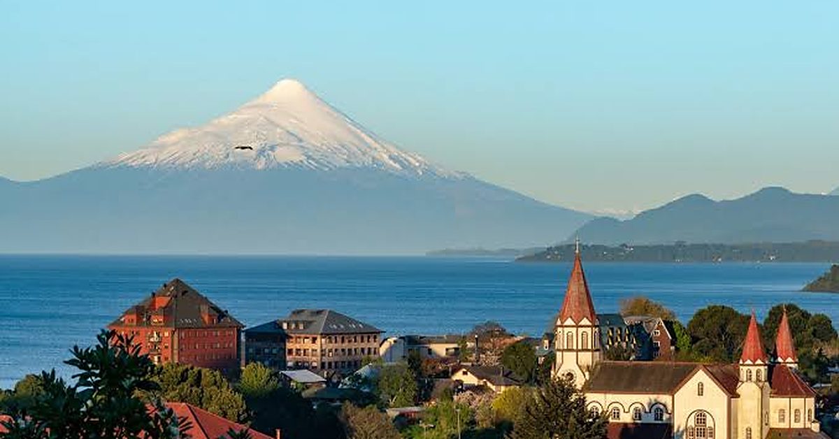 El volcán Osorno nevado sobre el lago Llanquihue, con los techos y la iglesia de Puerto Varas en primer plano.