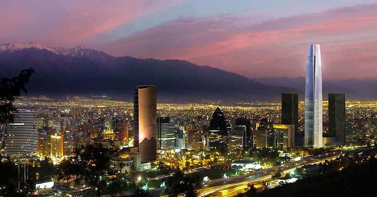 Santiago al atardecer: el skyline iluminado con su torre más alta y la cordillera nevada al fondo.